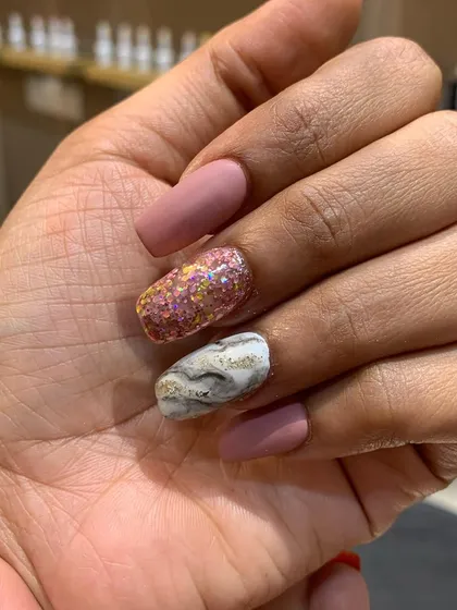A beautiful combination of textures, featuring matte pink nails, a chunky rose gold glitter accent, and a white marble design with gold veining.