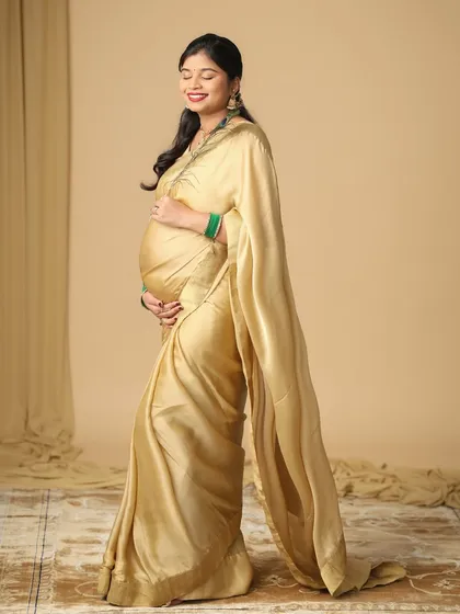The elegance of a mom-to-be in a simple, beautiful golden saree. This studio shot captures the peaceful and glowing moments of pregnancy with a touch of traditional grace.
