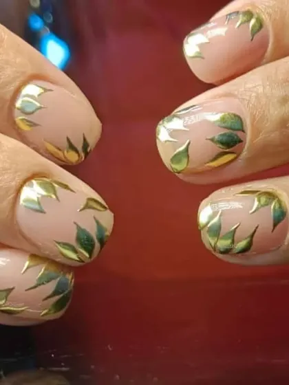A creative design featuring a sheer nude base covered in metallic gold and green leaf patterns.