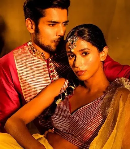 An intimate and artistic portrait of a couple. The bride's makeup features a traditional maang tikka and glowing skin, while the groom's look is clean and defined, creating a beautiful, cohesive image.