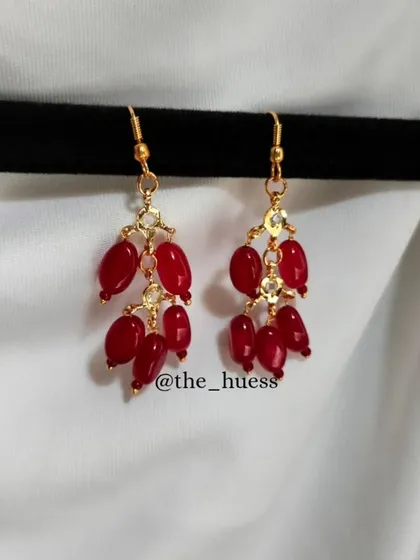 A close-up of the 'रेशमी' (Reshmi) earrings in a vibrant red. These are lightweight and easy to wear every day.