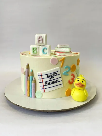 An adorable school-themed cake for a third birthday. This design celebrates learning with fondant ABC blocks, colored pencils, and a cute rubber ducky.