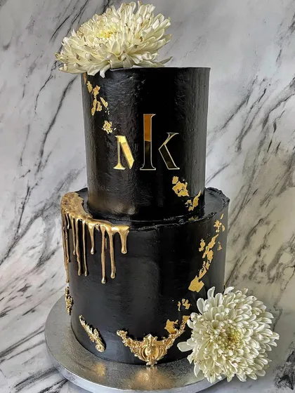 This two-tier black and gold cake is a perfect example of my modern and luxe style. I used a deep black buttercream to create a dramatic canvas, then added a custom gold monogram, delicate gold leaf accents, and a striking gold drip effect for a truly showstopping centerpiece.