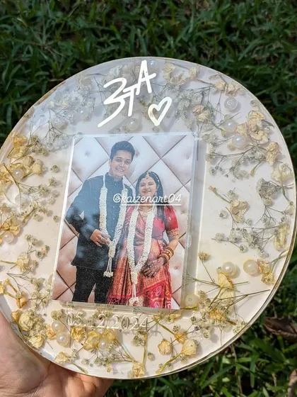 A full view of the 8-inch circular plaque with white and yellow flowers. It comes with a stand, making it easy to display this beautiful memory anywhere in your home.