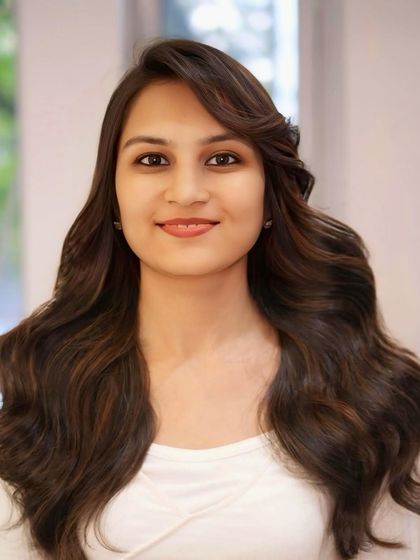 A smiling portrait of our client, happy with her new rich brown hair color and soft, flowing style.