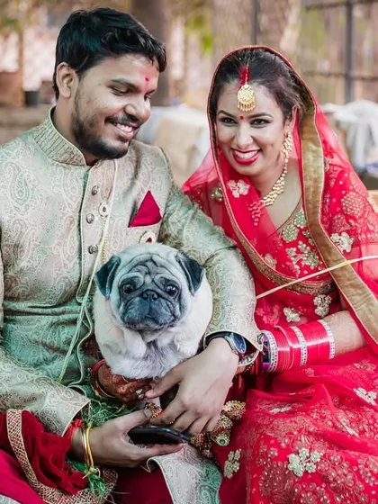 A happy family portrait on the wedding day, featuring the couple and their adorable pug. Everyone is smiling for the camera, capturing a moment of pure joy.
