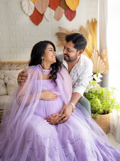 A joyful and candid moment between a couple during their maternity shoot, sharing a laugh and a loving gaze.