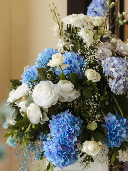 A stunning close-up of a floral arrangement, showing the rich texture and color variation of the blue and white hydrangeas and roses.