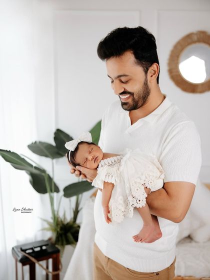 A happy father cradles his sleeping baby. The natural light and simple setting make this a warm and authentic portrait.