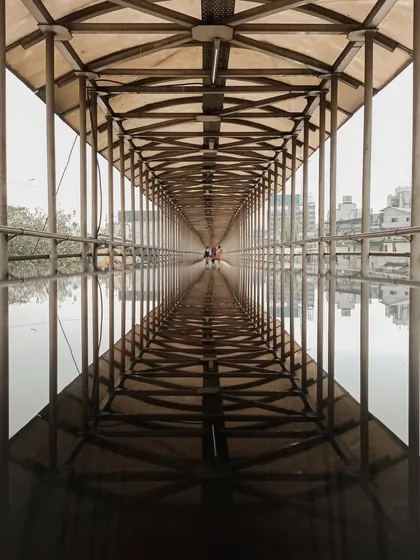 A perfectly symmetrical shot of a foot-over bridge and its reflection in a puddle. The leading lines create a mesmerizing "infinity" effect, turning a mundane structure into a piece of art.