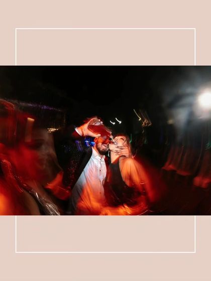 An artistic, motion-blur shot of the couple during the party. The streaks of red light and a champagne pour create a dynamic and abstract image of celebration.