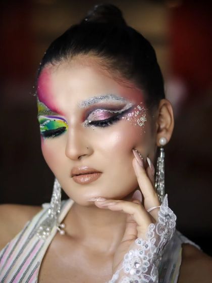 An artistic pose that highlights the details of the makeup and the long, pearl earrings.