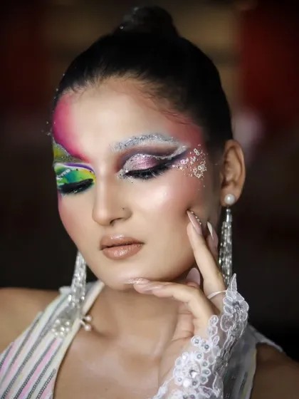 An artistic pose that highlights the details of the makeup and the long, pearl earrings.