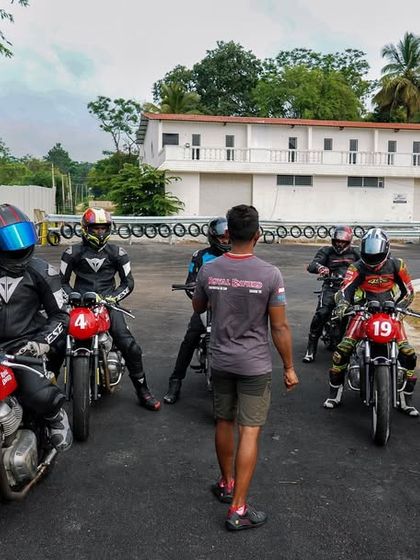 A coach leads a group of riders through a drill on the track. Our structured sessions are designed to build skills progressively, starting with fundamentals and moving to more advanced techniques.