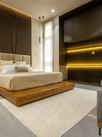 This bedroom features a custom floating bed on a wooden platform, creating a sense of spaciousness. We used layered lighting, including back-lit panels and pendant lamps, to create a warm and inviting ambiance perfect for unwinding.