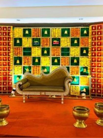 A traditional Seemantham stage with a unique checkerboard backdrop and an elegant chaise lounge. The warm lighting and brass pots add to the classic and inviting ambiance.