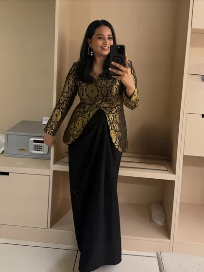 A selfie showing off an elegant black and gold brocade jacket paired with a draped skirt. This is a perfect outfit for hosting a wedding reception or a glamorous cocktail evening.