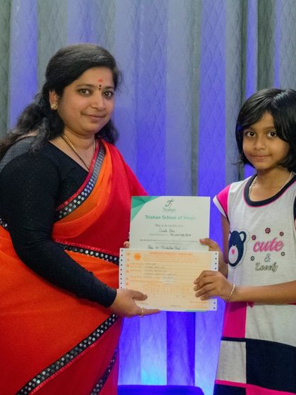 A student receives her graded music exam certificate at a ceremony.