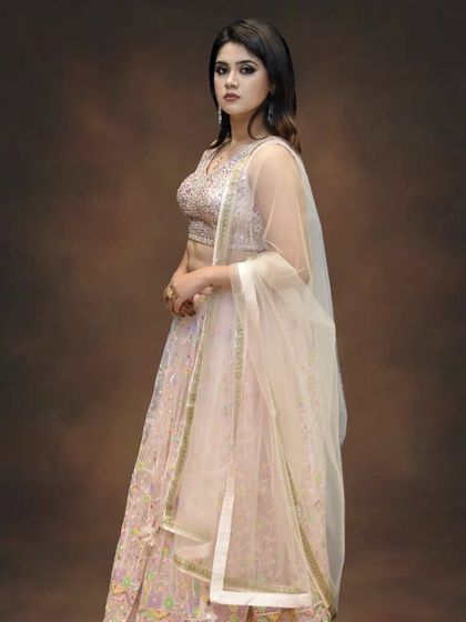 A closer view of the blush pink lehenga, highlighting the delicate embroidery on the choli and the fine net dupatta. It’s all about subtle, elegant details.