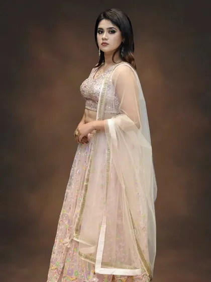 A closer view of the blush pink lehenga, highlighting the delicate embroidery on the choli and the fine net dupatta. It’s all about subtle, elegant details.