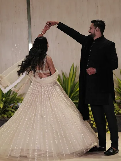 A romantic dance between the couple. The bride's elegant white lehenga and soft makeup create a dreamy and magical look for their reception or sangeet.