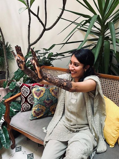A happy, candid shot of a bride showing off her modern lotus-themed mehndi.