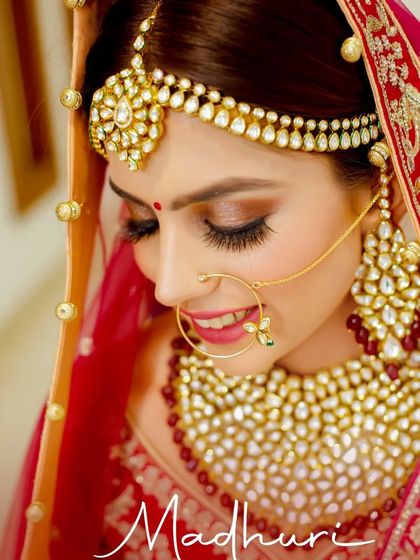 A breathtaking close-up of the bride Madhuri. This portrait focuses on her flawless makeup, traditional jewelry like the nath and maang tikka, and her serene expression.