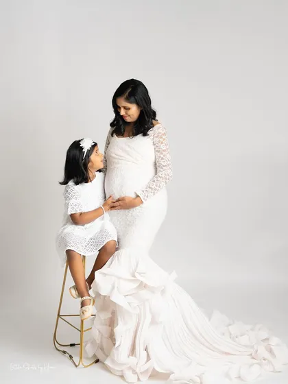 A beautiful pose showing the connection between mother and daughter during a maternity session. Dressed in elegant white gowns, they share a quiet look of love and anticipation.
