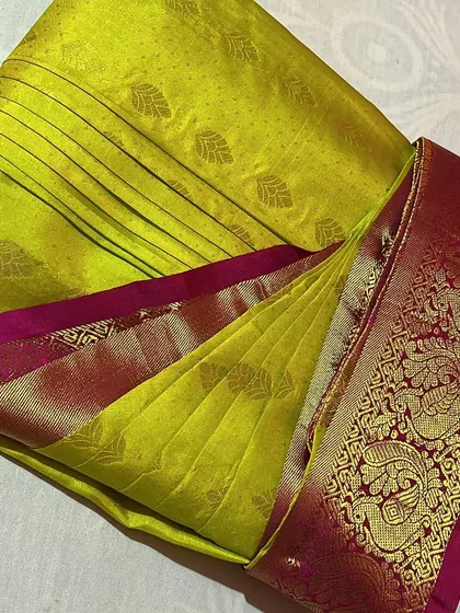 A close-up of a lime green silk saree, showing the perfect pleats and folds.