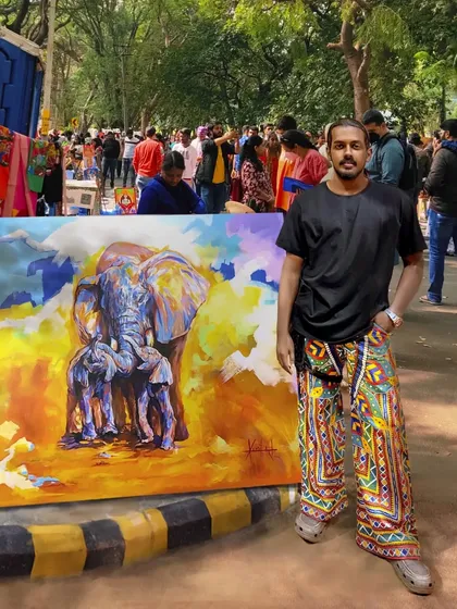 Me with my large-scale elephant painting, 'Mother Love', at an outdoor art fair. This piece, with its abstract colors and emotional theme, always draws a crowd.