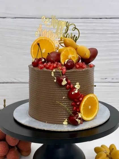 A unique, fruit-loaded anniversary cake. This chocolate cake is topped with fresh oranges, cherries, and pomegranates for a vibrant and delicious treat.