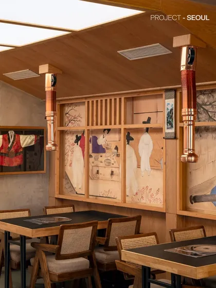 A detailed look at the dining area, where custom murals and framed traditional garments add layers of storytelling. The warm wood paneling and woven chair backs contribute to a tactile and inviting environment.