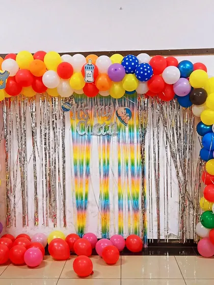 The full view of the colorful "Chatti" ceremony decoration, with a multi-colored balloon arch and a shimmering silver and rainbow backdrop.
