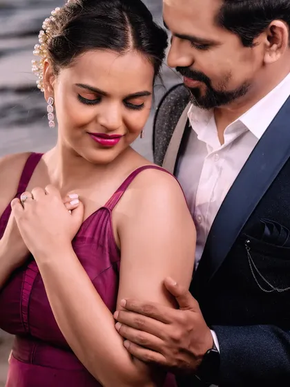 A quiet, intimate portrait against the soft evening light by the sea. The focus is on their gentle interaction and the romantic mood of the setting.