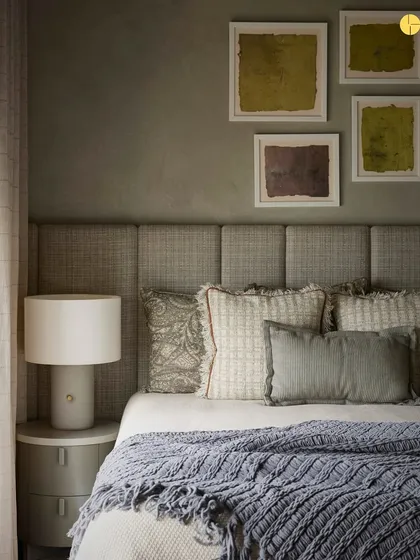 In the guest bedroom of 'Pad by the Bay,' an olive green accent wall and layered textiles create a cozy and welcoming sanctuary. The design focuses on comfort, with plush pillows and soft throws making visitors feel right at home.