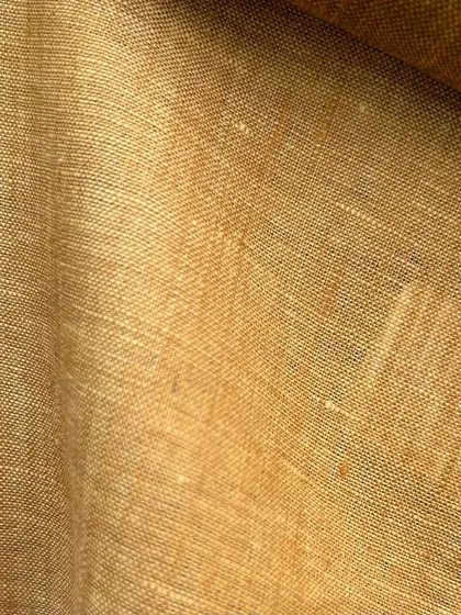 A close-up of a beautiful mustard-colored linen fabric. Linen offers a unique texture and is exceptionally breathable for summer wear.
