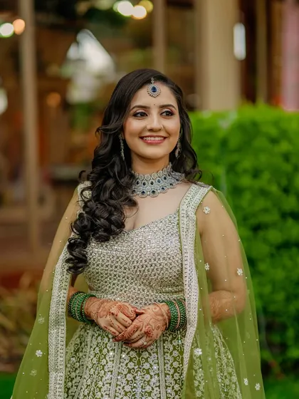 A fresh and modern sangeet look in a pastel green lehenga. The makeup is luminous with soft curls and a statement maang tikka.