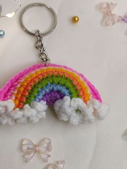 A vibrant rainbow keychain with fluffy white clouds, because who doesn't love carrying a rainbow around?