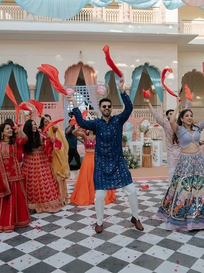 A high-energy group performance at a Mehendi, with everyone waving red handkerchiefs. Using simple props like this can add a great pop of color and energy.