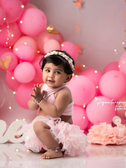 Another adorable shot from the pink-themed first birthday, capturing the baby girl's curiosity and delight.