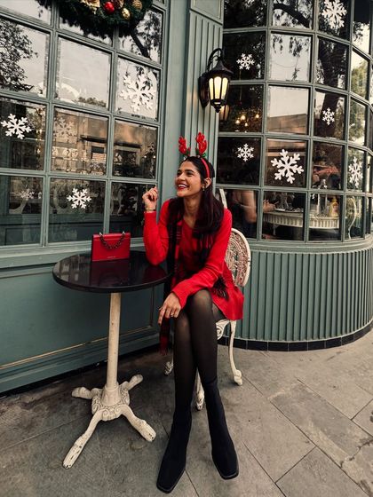 A festive moment outside a cafe decorated for Christmas. The reindeer antlers add a playful touch to my coordinated red and plaid holiday outfit.