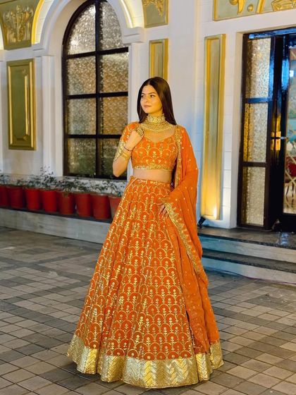 A confident pose in the orange Banarasi lehenga, a perfect outfit for any wedding guest or bridesmaid.