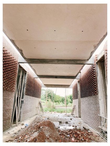An interior view of a corridor during construction, with patterned brick walls on either side. This shows how I use materials to create texture and play with light, even in transitional spaces.