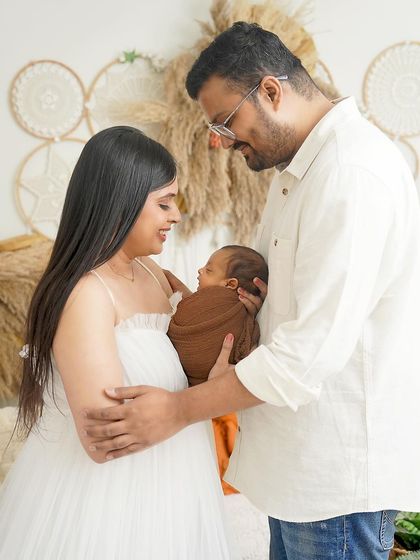 A candid moment of love between new parents and their baby. They gaze at their son with adoration in this light-filled, boho-inspired photograph.