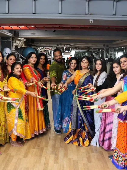 The whole group posing together with their dandiya sticks, creating a beautiful and colorful memory.
