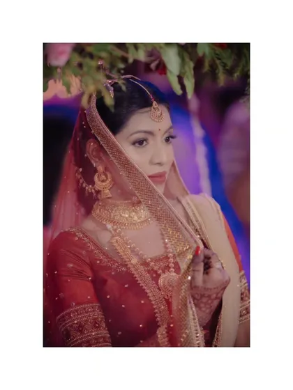 A beautiful portrait of the bride, Alka, her face partially obscured by her veil, creating a sense of mystery and traditional beauty.