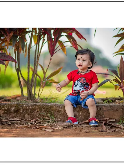 A natural portrait of a toddler sitting on a ledge in a garden. Outdoor settings provide beautiful, natural backdrops for children's photography.