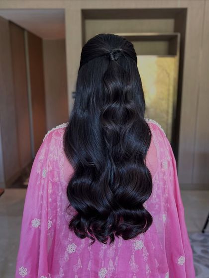 A simple yet elegant half-up style with a neat knot at the crown and classic, glossy waves.