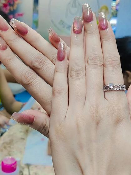 A lovely set of long, square nails with a reddish-brown ombre effect and a touch of gold glitter. This is a warm and sophisticated look.