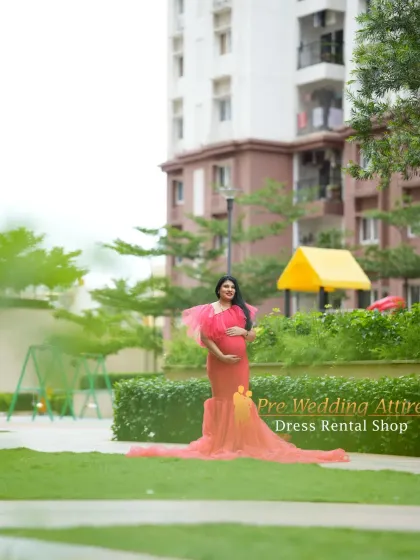 A full-length shot of the red mermaid gown in a park, showing how the train spreads out beautifully on the grass. This dress offers a stunning combination of a figure-hugging fit and a dramatic, flowing base.